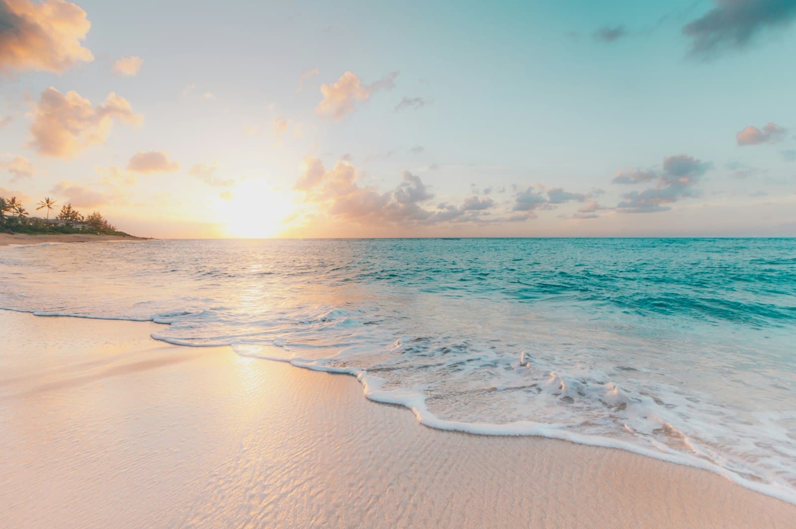 A quiet shoreline at sunrise with pale sand and clear water